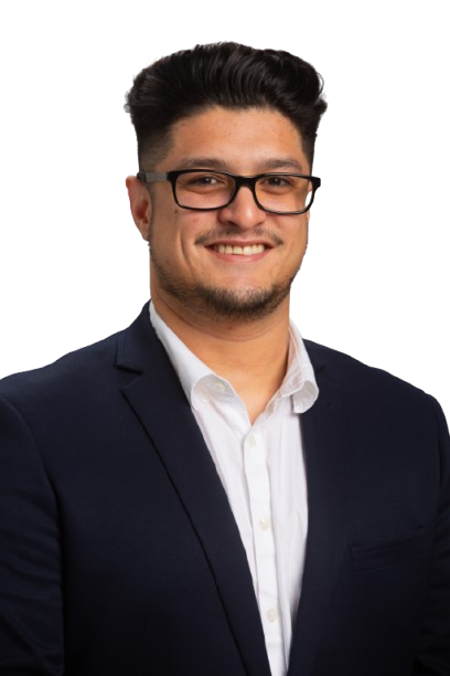 A man in a blue blazer with a UFG pin and a checkered shirt, smiling at the camera against a white background.